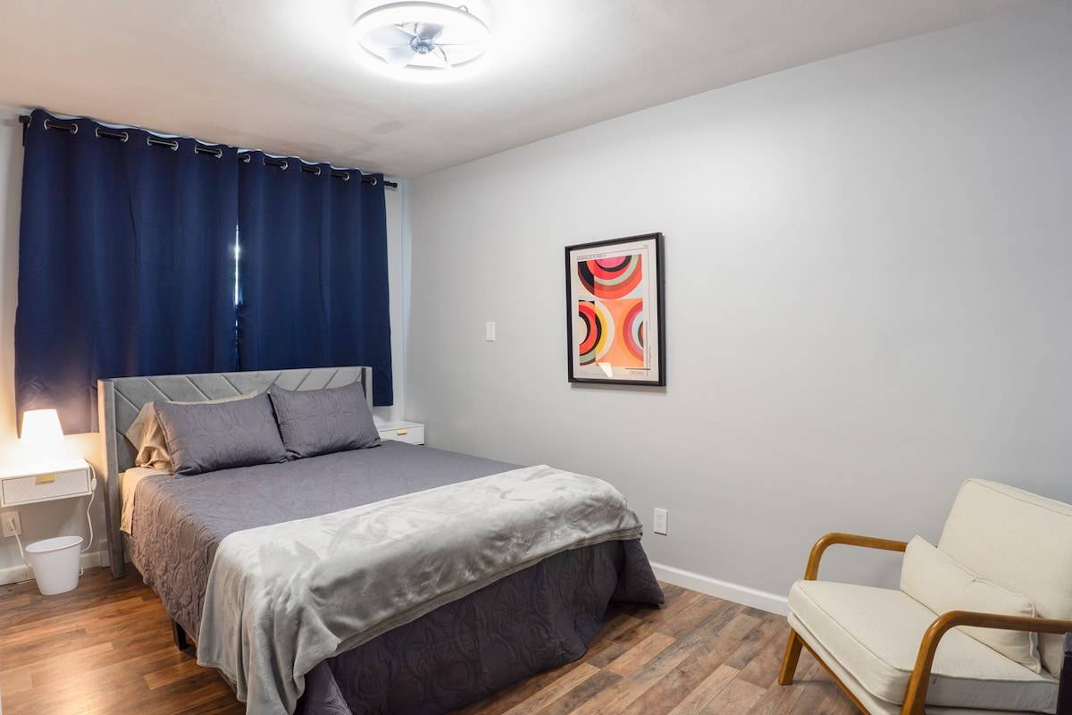 Queen bedroom with reading chair and room-darkening curtains